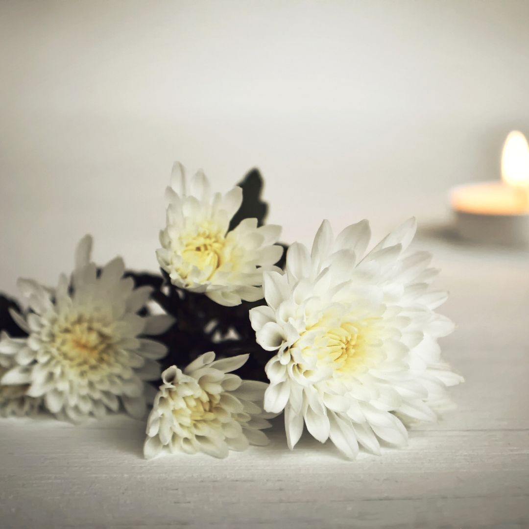 White flowers and a candle burning in the background. 